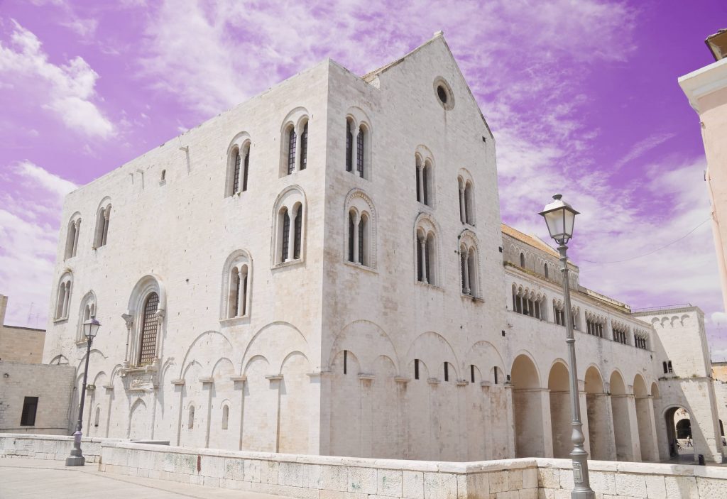 Front view of the historic St. Nicholas Basilica in Bari Vecchia, showing its grand Romanesque facade and medieval stone towers.